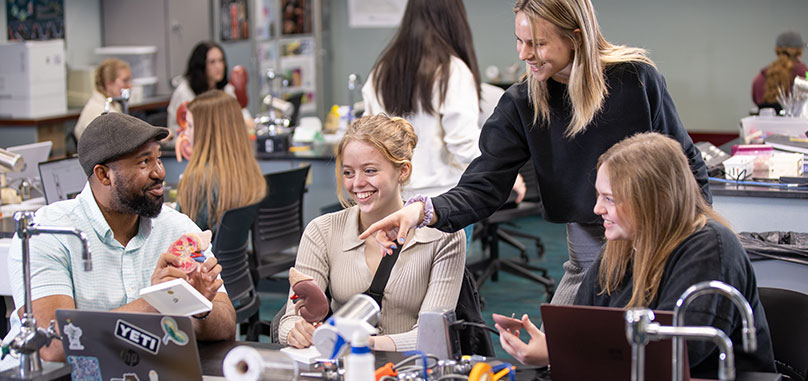 Students talking in class around computer